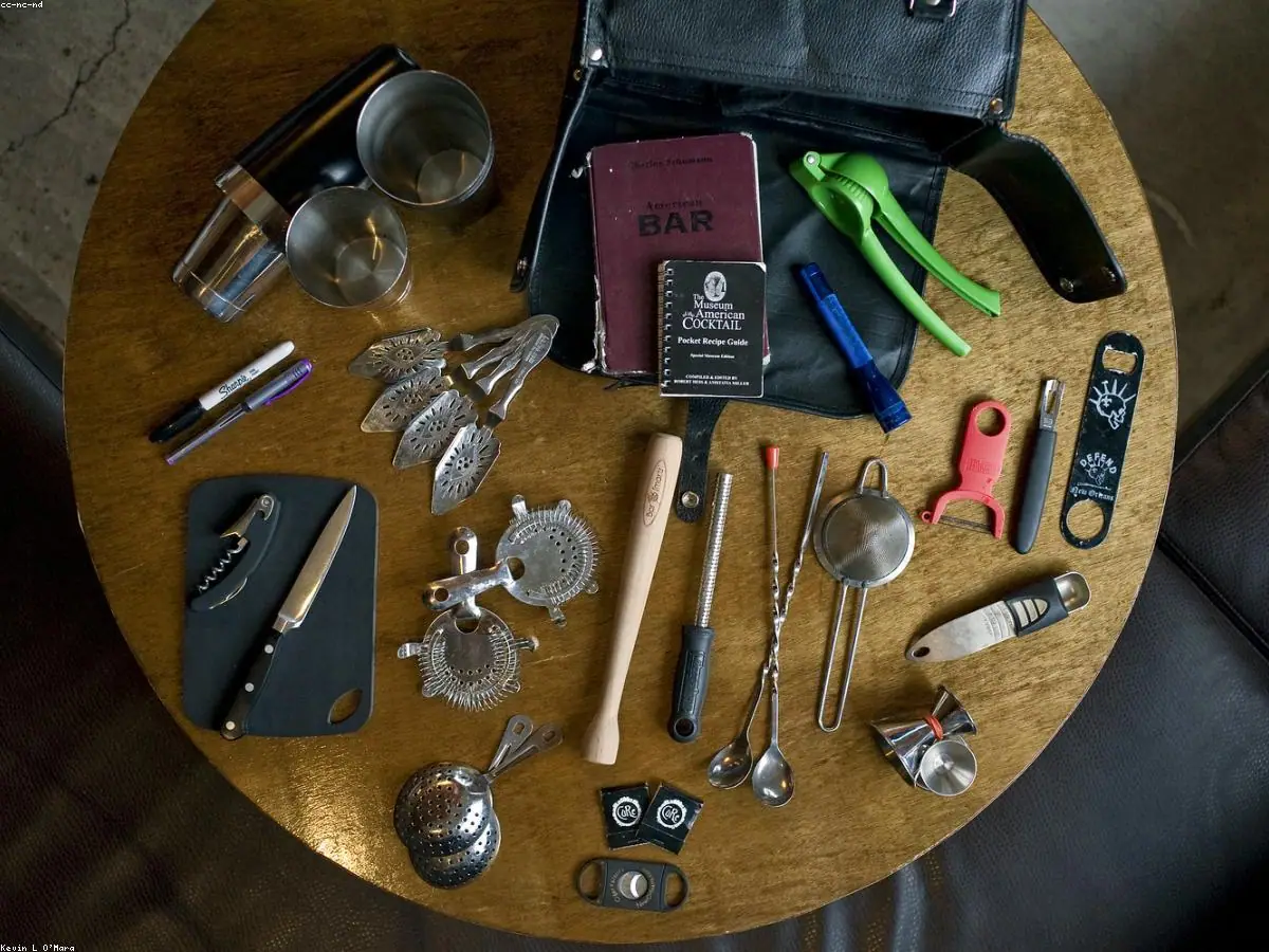 Flat-lay of the Pro Bartender Kit: shaker tins, jigger, strainers, bar spoon and muddler in a roll-up case